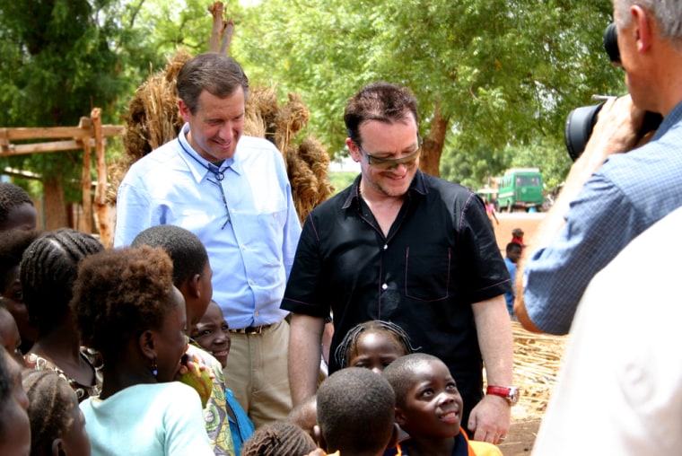 Brian Williams and Bono greet children on a road outside Bamako, Mali.